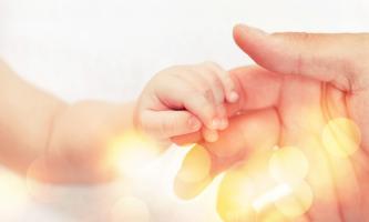 Proposer au bébé un doigt à tenir et sourire pour renforcer l'association entre le toucher et le stimulus visuel (Visuel Adobe Stock 272777450)